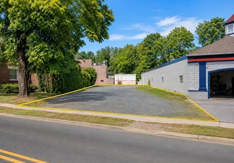 Terreno plano de grava marcado en amarillo sobre South Avenue, junto a un edificio comercial de un piso