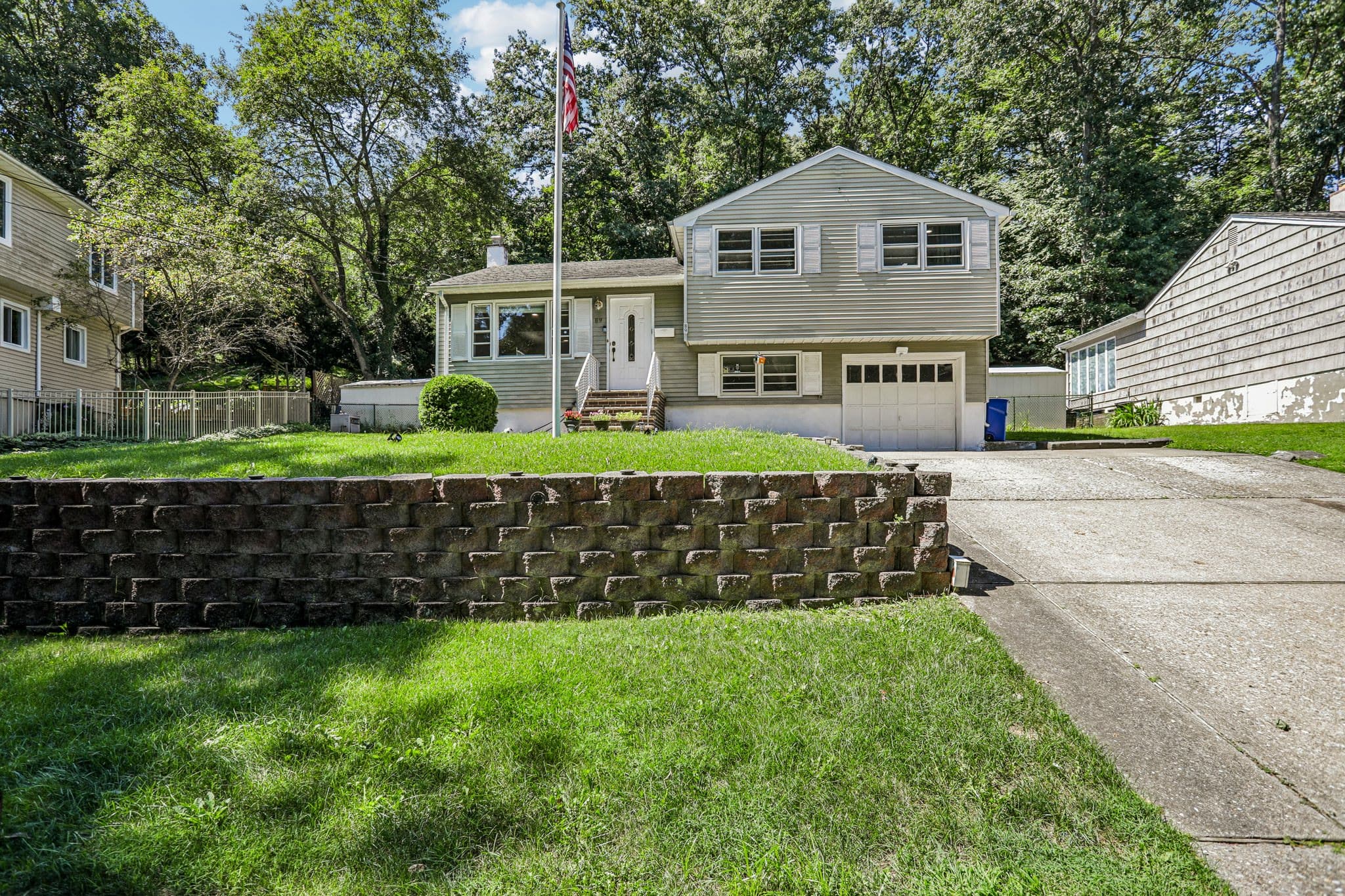 Casa de varios niveles con un muro de piedra y césped al frente en Bloomingdale, Nueva Jersey